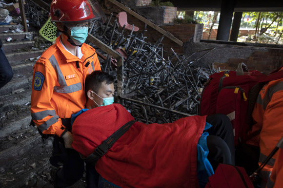 20일 홍콩 이공대에서 시위대로 추정되는 한 남성이 의료진의 들것에 실려 불에 탄 잔해로 가득한 교정을 지나 밖으로 옮겨지고 있다. AP 연합뉴스