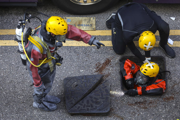 홍콩 소방당국의 잠수부 요원이 20일 하수구 맨홀 구멍 안으로 들어가고 있다. 홍콩 EPA 연합뉴스    
