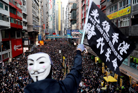 홍콩 시위 사태 6개월을 맞은 지난 8일 시민 80여만명이 거리 집회에 참여한 가운데 한 시위자가 저항의 상징인 ‘가이포크스’ 가면을 뒷머리에 쓰고 ‘광복홍콩, 시대혁명’(홍콩에 자유를, 이 시대에 혁명을)이라고 적힌 깃발을 흔들고 있다. 홍콩 로이터 연합뉴스