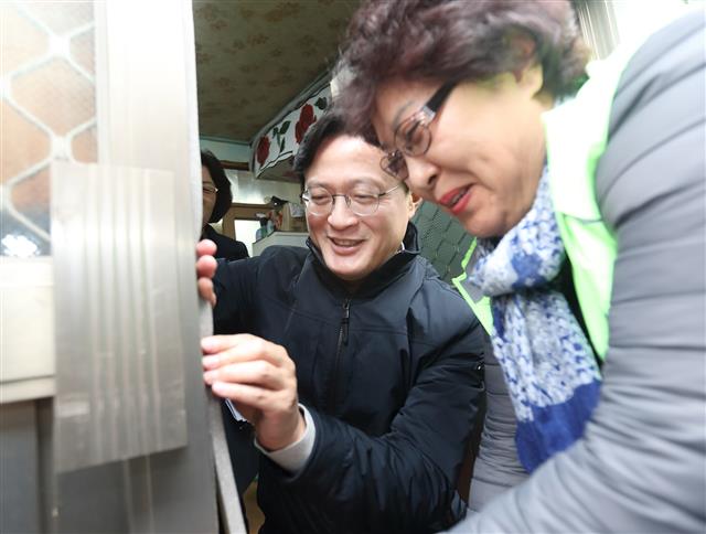 채현일(왼쪽) 서울 영등포구청장이 지난 9일 영등포구 양평1동의 한 쪽방을 방문해 현관문에 직접 문풍지를 설치하고 있다. 영등포구 제공