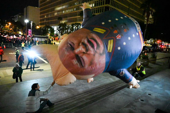 도널드 트럼프 미국 대통령에 대한 하원 탄핵소추안 표결을 하루 앞둔 17일(현지시간) 미국 캘리포니아주 로스앤젤레스에서 탄핵을 지지하는 시위대가 시위를 벌이고 있다. AFP 연합뉴스