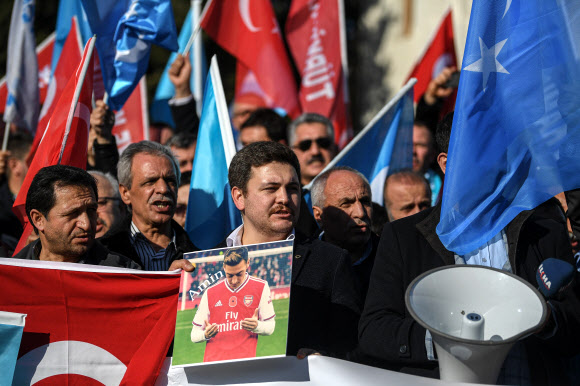 위구르족 지지자들이 지난 14일(현지시간) 터키 이스탄불의 베야지드 광장에서 동투르키스탄 깃발을 든 채 메수트 외질이 무슬림 기도를 올리는 사진 팻말을 들고 그의 발언을 지지하는 시위를 벌이고 있다. 이스탄불 AFP 연합뉴스 
