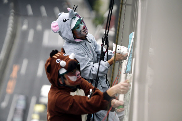 돼지(왼쪽)와 쥐의 12궁도 동물 복장을 한 창문 청소부들이 19일(현지시간) 일본 도쿄에서 호텔의 유리 외관을 청소하고 있다. AP 연합뉴스
