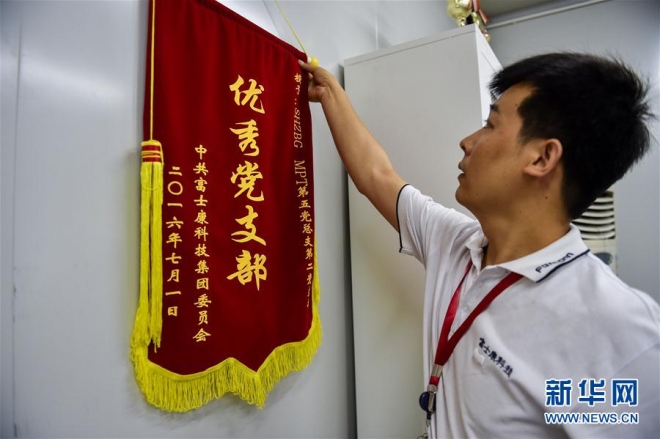 폭스콘 당지부 서기인 자오베이민이 2017년 9월 14일 화난검측센터 사무실에서 ‘우수 당지부’라는 깃발을 만지고 있는 모습. 신화통신 캡처