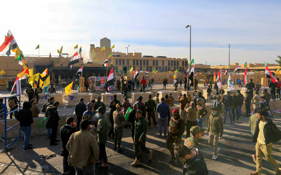 이라크 시위대가 바그다드 미국 대사관 앞에 진을 치고 있다. 노란 깃발은 최근 미국의 공습을 받은 친이란계 무장단체 카타이브 헤즈볼라의 상징. 바그다드 로이터 연합뉴스