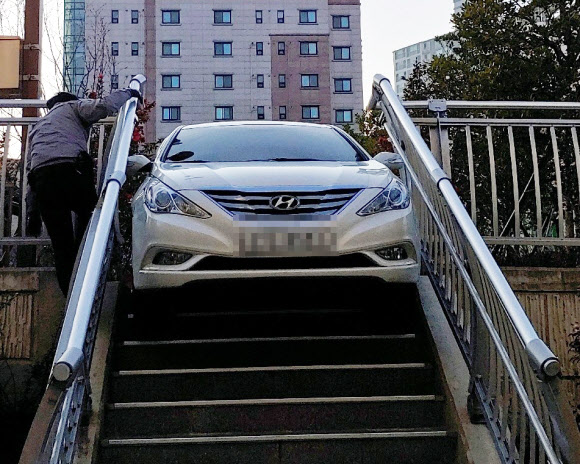 지난 11일 오후 부산 한 공원 계단에 걸쳐 있는 승용차. 운전자가 술에 취해 계단을 공원 진입도로로 착각한 것으로 경찰은 보고 있다. 부산진경찰서 제공