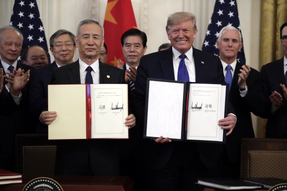 도널드 트럼프(오른쪽) 미국 대통령과 류허 중국 부총리가 15일(현지시간) 워싱턴DC 백악관에서 미중 1단계 무역 합의안에 서명한 뒤 이를 들어보이고 있다. 연합뉴스