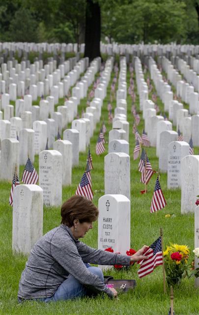 미국에서 시신을 묻거나 태우는 대신 땅에 도움이 되는 방식으로 처리하는 ‘시신 퇴비화’가 5월부터 시행되는 가운데 한 여성이 버지니아주 알링턴 국립묘지에 안장된 남편의 묘비 옆에 앉아 있다. 미국에서는 남북전쟁 당시 전사한 군인의 시신을 보존하기 위해 방부 처리를 시작했는데, 환경론자들은 “이 방식이 여러 가지 문제를 낳고 있다”고 비판한다. UPI 연합뉴스