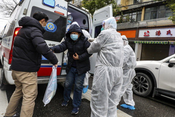 27일(현지시간) 중국 후베이성 우한에서 의료진이 환자를 구급차에서 내려주고 있다. AP 연합뉴스