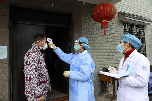 지난달 27일 중국 항저우에서 보건당국 관계자가 후베이성에서 돌아온 주민의 발열 여부를 확인하고 있다. AP 연합뉴스