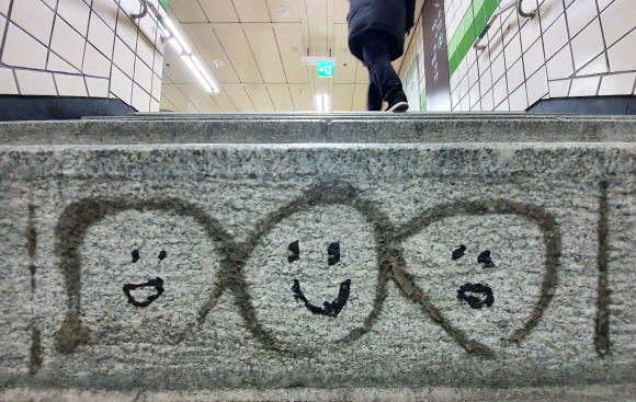 서울의 한 지하철역. 누구일까, 언제부터일까…. 안내판이 떨어지고 남은 접착제의 흔적에 서로 다른 표정의 세 사람 얼굴이 그려져 있다. 누군가는 지저분하다 할지 모르지만, 누군가는 생각지 못한 한 사람의 재미난 상상력 덕분에 출근길에 미소를 짓는다. 도준석 기자 pado@seoul.co.kr