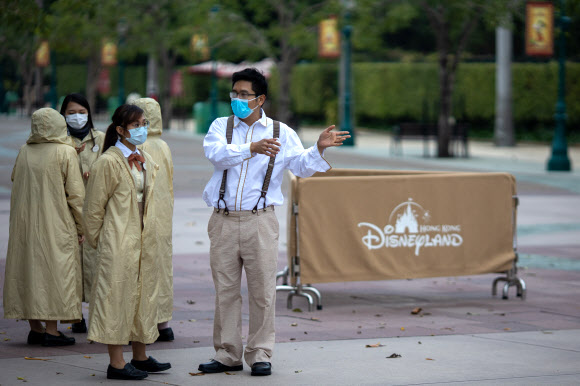 신종 코로나바이러스 감염증의 확산으로 문을 닫은 홍콩 디즈니랜드 입구에서 마스크를 낀 직원들이 얘기를 나누고 있다. 홍콩 EPA 연합뉴스