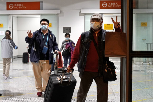 홍콩 항만에 해상 격리됐던 크루즈 유람선 월드 드림 호 승객들이 9일 배에서 내려도 좋다는 허락이 떨어져 짐을 챙겨 빠져나오며 손가락으로 V 자를 그려보이고 있다. 홍콩 AP 연합뉴스 