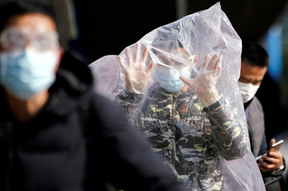 중국 내 신종 코로나바이러스 감염증 환자가 4만명을 넘어선 지난 9일 상하이의 한 기차역에서 마스크를 착용한 여성이 감염병 전파를 막고자 온몸에 대형 비닐 봉지를 덮어쓴 채 역을 빠져나오고 있다. 상하이 로이터 연합뉴스