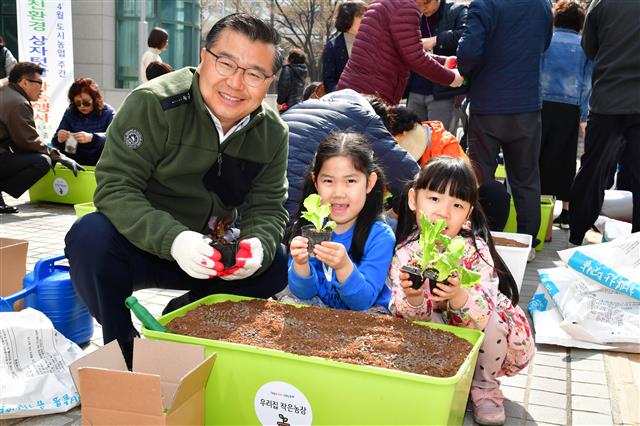 류경기(왼쪽) 서울 중랑구청장이 지난해 4월 구청 광장에서 열린 ‘상자텃밭 나눔행사’에서 어린이들과 함께 상추 모종을 심으면서 활짝 웃고 있다. 중랑구 제공