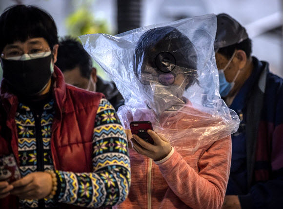 한 여성이 11일(현지시간) 중국 광둥성 광저우에서 코로나바이러스로 부터 보호하기 위한 마스크를 구입하기 위해 보호용 비닐봉지를 얼굴에 쓰고 약국에서 줄을 서서 기다리고 있다. EPA 연합뉴스