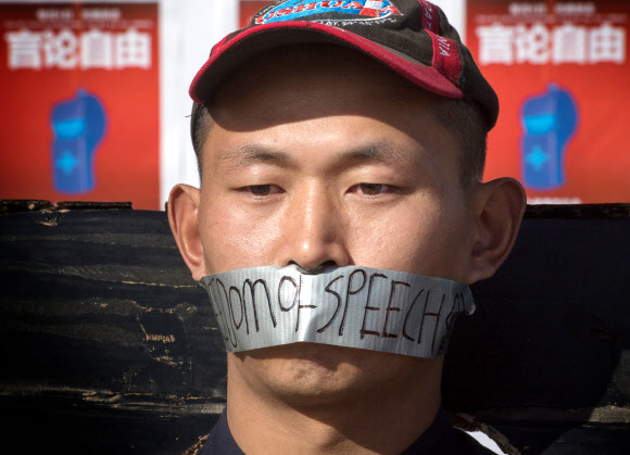 중국인 유학생이 15일(현지시간) 미국 캘리포니아주 웨스트우드의 UCLA 캠퍼스 밖에서 진행된 우한의 의사 리원량 추모 행사 도중 중국에서의 표현의 자유를 촉구하는 마스크를 쓴 채 굳은 표정을 짓고 있다. 　웨스트우드 AFP 연합뉴스
