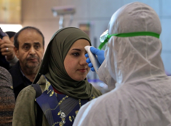 이란을 떠난 항공기 편으로 이라크 나자프 공항에 도착한 여행객들이 21일(현지시간) 응급 의료요원으로부터 체온을 점검받고 있다. 나자프 AP 연합뉴스 