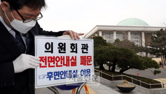 24일 국회 직원들이 의원회관 안내실 폐문을 알리는 문구를 붙이고있다. 2020. 2. 24. 정연호 기자 tpgod@seoul.co.kr