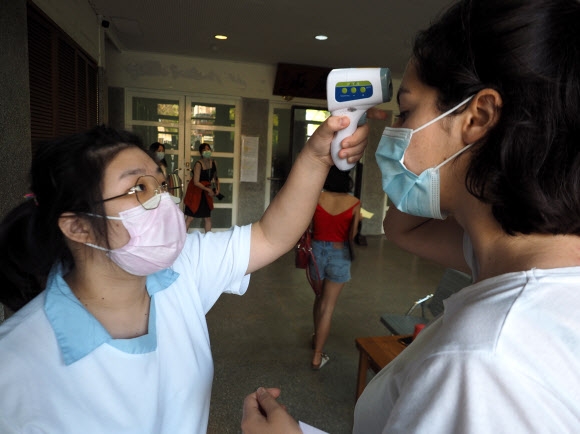 24일 대만 타이베이의 한 대학에서 신학기가 시작한 가운데 의료진이 한 유학생의 체온을 측정하고 있다. 대만은 25일부터 한국에서 대만으로 입국하는 모든 여행객에 대해 14일간 의무 격리시키겠다고 밝혔다. 2020.2.24  EPA 연합뉴스