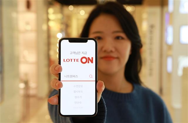 모델이 롯데의 e커머스 온라인몰 사업 ‘롯데ON’이 켜진 스마트폰을 들고 포즈를 취하고 있다. 롯데지주 제공