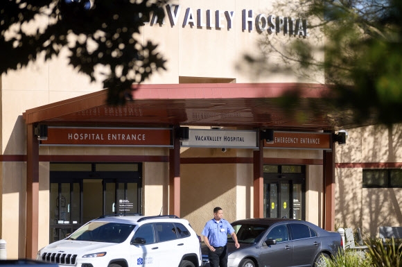 27일(현지시간) 한 여성이 코로나19 확진을 받은 미국 캘리포니아의 한 병원에서 경비가 걸어나오고 있다. AP통신