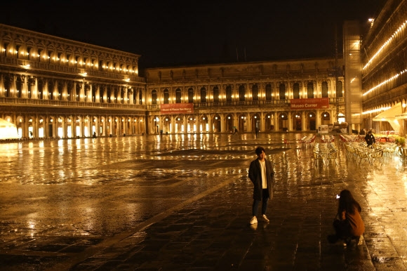 비 오는 2일(현지시간) 이탈리아 베네치아의 산 마르코 광장이 텅 빈 가운데 관광객들이 사진을 촬영하고 있다. 베네치아 AP 연합뉴스