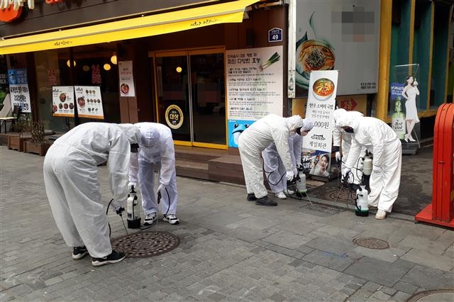 서울 중구에서 나온 소독업체 용역직원들이 지난달 26일 중구 북창동 골목의 맨홀 내부를 방역하고 있다. 중구 제공