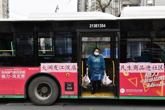 중국 후베이성 우한에서 5일(현지시간) 주민들이 주문한 상품을 배달하는 직원이 버스에서 짐을 들고 내리고 있다. 2020.3.5  로이터 연합뉴스