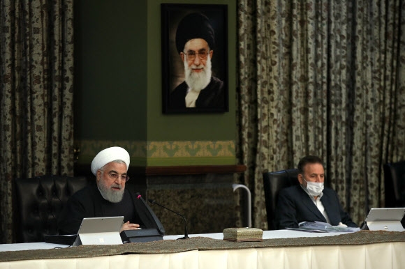 하산 로하니(왼쪽) 이란 대통령이 11일 테헤란에서 내각 회의를 주재하며 열변을 토하고 있다. 위 초상화는 아야톨라 알리 하메네이 최고 지도자의 것이다. 이란 대통령궁 제공 AFP 연합뉴스