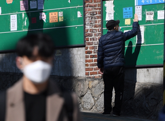 코로나 19 여파로 대학교 개강 연기와 중국인 유학생 감소가 이어지고 있는 15일 서울 중앙대학교 인근에서 원룸 임대인이 자신이 붙인 하숙 및 자취생을 모집하는 게시물을 정돈하고 있다. 2020.3.15 오장환 기자 5zzang@seoul.co.kr