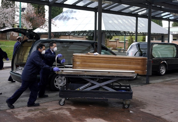 스페인 마드리드 라 알무데나 공동묘지의 인부들이 23일(현지시간) 코로나19에 감염돼 숨진 이의 관을 운구하고 있다. 마드리드 로이터 연합뉴스 
