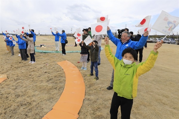 2020 도쿄올림픽 성화를 실은 특별수송기가 20일 미야기현의 항공자위대 마쓰시마 기지에 착륙하자 지역 주민들이 일장기를 흔들며 환호하고 있다. 2020.3.20 