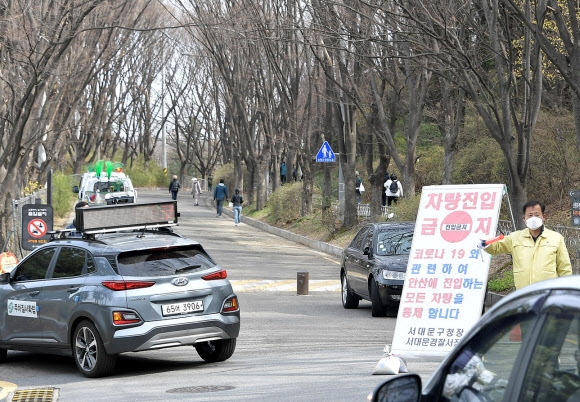 서울 서대문구청 직원들이 28일 안산 자락길 부근에서 산책 나온 시민들에게 마스크 착용과 사회적 거리두기를 안내하고 있다. 서대문구는 안산에 나들이객이 몰리는 것을 방지하기 위해 매년 4월 초 개최해 오던 ‘안산 자락길 벚꽃음악회’를 올해는 열지 않기로 했다. 연합뉴스.