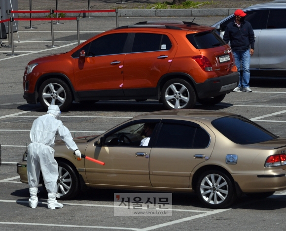 5일 서울 송파구 잠실종합운동장에 마련된 해외입국자 전용 선별진료소에서 방역 관계자가 자가용을 타고 코로나19 검진을 받으러 온 시민을 안내하고 있다. 박지환 기자 popocar@seoul.co.kr