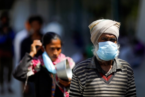 인도 뉴델리 덮친 코로나19  인도 전역에 3주간 국가봉쇄령이 내려진 가운데 뉴델리에서 4일(현지시간) 시민들이 마스크를 쓴 채 음식이 있는 피난처로 향하고 있다. 로이터 연합뉴스 2020-04-04 19:40:02