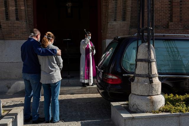 6일(현지시간) 스페인 마드리드에 있는 라알무데나 공동묘지 화장장 앞에서 한 가톨릭 신부가 코로나19 희생자의 관이 실린 운구차를 향해 장례 미사를 집전하고 있다. 장례식 유족은 두 명만 보인다. 5분가량이면 끝나는 드라이브 스루 장례식이다. 마드리드 AP