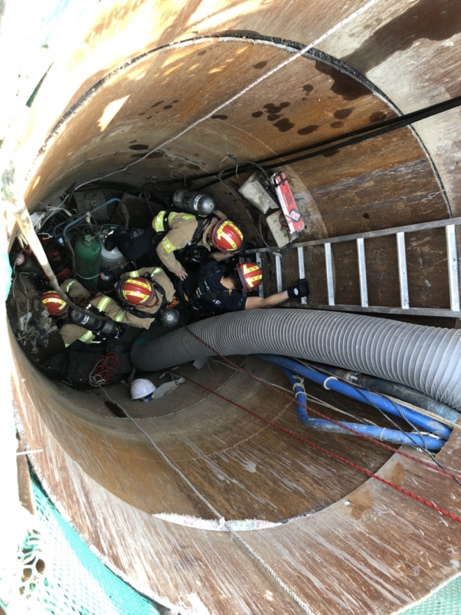 119 구조대원들이  맨홀 바닥에 쓰러진 인부 구조 작업을 벌이고 있다.<부산소방재난본부 제공>. 