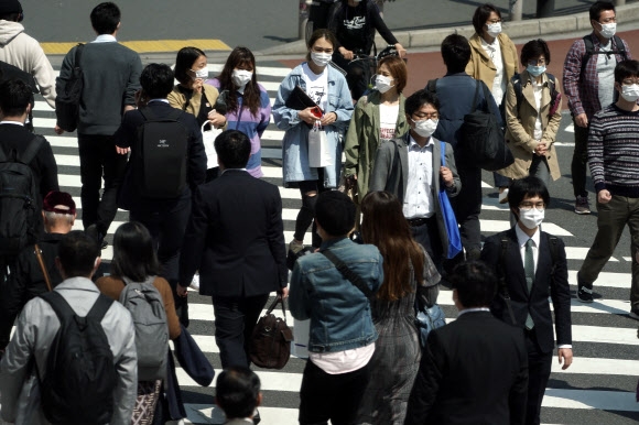 일본 도쿄의 직장인들이 9일 마스크를 모두 쓴 채 횡단보도를 건너고 있다. 아베 신조 총리는 지난 7일 도쿄를 비롯한 7개 현에 코로나19 긴급사태를 선언했다. 도쿄 AP 연합뉴스 