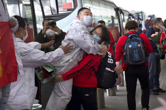 지난 8일 중국 허베이성 우한의 병원에서 일해온 의료진(빨간 옷)이 귀향을 위해 공항에 도착해 동료와 포옹을 하며 기뻐하고 있다. AP통신
