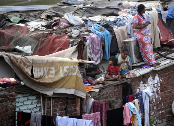 인도 뭄바이에서 지난 11일 시민들이 코로나19 바이러스 확산을 막기 위한 봉쇄정책에 판잣집 지붕에서 쉬고 있다. 연합뉴스 