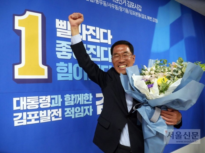 김주영 김포갑 당선인이 당선이 확정된 뒤 손을 치켜들며 환하고 웃고 있다.