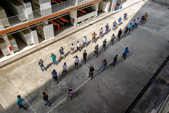싱가포르의 외국인 근로자들이 지난 15일(현지시간) 기숙사 ST로지 앞마당에서 사회적(물리적) 거리 두기를 지키며 체온 측정 차례를 기다리고 있다. 로이터 자료사진 연합뉴스