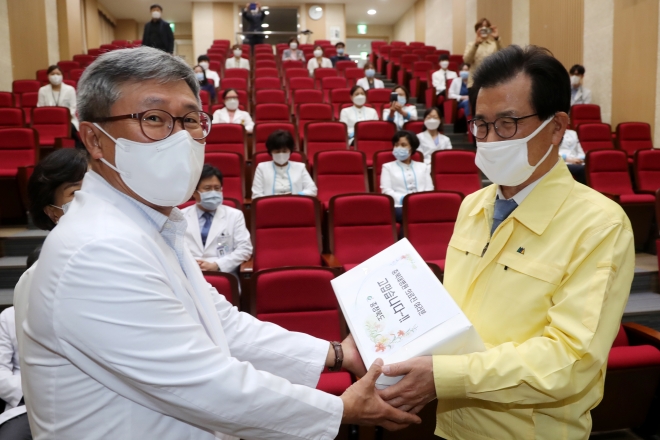 이시종(오른쪽) 충북지사가 20일 충북대병원을 방문해 코로나19와 싸우고 있는 의료진들을 격려한 뒤 간식을 전달하고 있다. 충북도 제공.