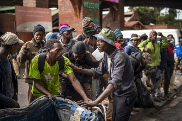 지난 13일 남아프리카공화국 요하네스버그에서 노숙자들이 무료 배식을 받기 위해 줄지어 서 있다. 요하네스버그 AP 연합뉴스