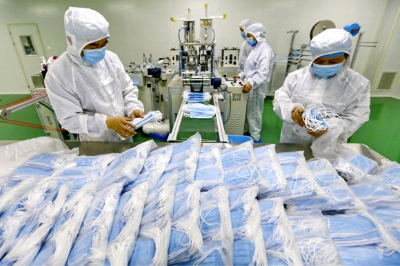 지난 2월 중국 남서부 쓰촨성 쑤닝시의 한 마스크 공장에서 직원들이 생산라인을 거쳐 나온 의료 마스크를 최종 점검하고 있다. 쑤닝 AP 연합뉴스