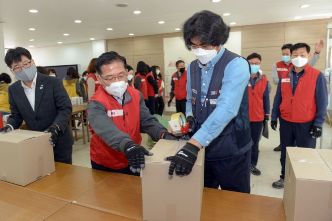 윤명훈(전무) 주재임원과 정남길(오른쪽) 노동조합위원장이 여성위생용품 박스를 포장하고 있다.