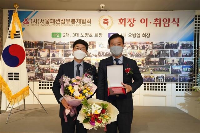 지난 23일 서울 성북구 1600개 의류봉제업체로부터 이승로(오른쪽) 성북구청장이 감사패를 받고 포즈를 취하고 있다. 성북구 제공