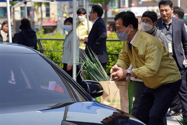 이승로 성북구청장이 지난 29일 구청 앞 성북천 일대에서 드라이브스루로 진행된 코로나19 피해 자매도시 농산물 판매장에서 파 등이 담긴 친환경 농산물 꾸러미를 건네고 있다. 성북구 제공