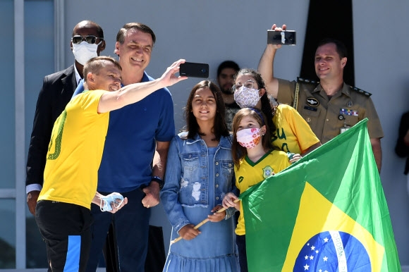 자이르 보우소나루(왼쪽 두 번째) 브라질 대통령과 딸 라우라(가운데)가 3일(현지시간) 수도 브라질리아의 플라날토 대통령궁 앞에서 지지자들과 함께 셀카를 찍기 위해 포즈를 취하고 있다. 브라질리아 AFP 연합뉴스